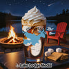 Drink with whipped cream, lake, campfire, and s'mores ingredients.