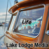 Wisconsin Life sticker on a wooden boat window with Lake Lodge Media text.