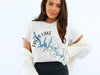 White t-shirt with blue Falls Lake map graphic and compass design, North Carolina.