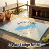 Rectangular glass cutting board featuring a blue Watson Lake map and compass graphic, displayed on a wooden outdoor bar.