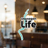 Okanagan Life sticker with turquoise water shape on a glass surface.