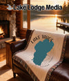 Woven blanket with Lake Tahoe map and compass rose on a leather couch.