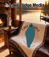 Woven blanket with Lake Mohave map and compass design on leather sofa.