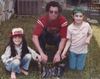 Three people posing with a bundle of fish outdoors.